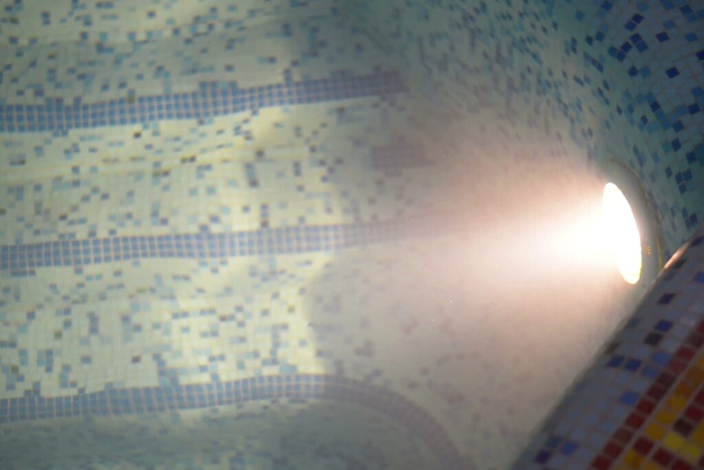 A light shining through a tiled pool, offering pool lighting ideas.