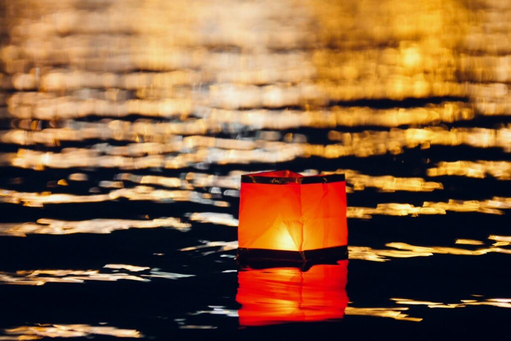 A red paper lantern floating in the water at night, perfect for pool lighting ideas.