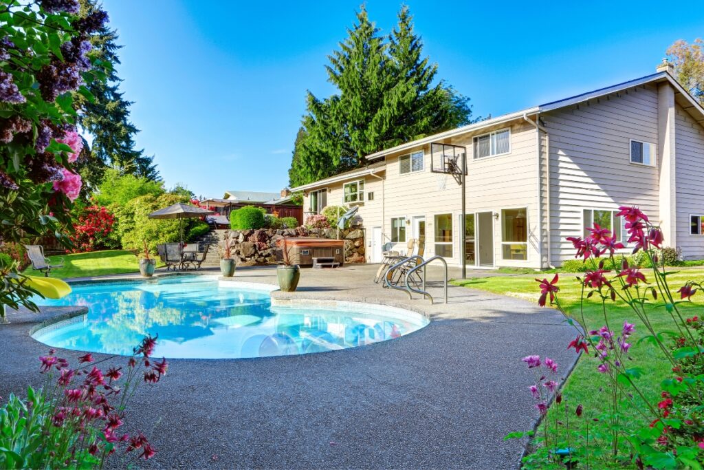 A home with a uniquely shaped swimming pool in the backyard.