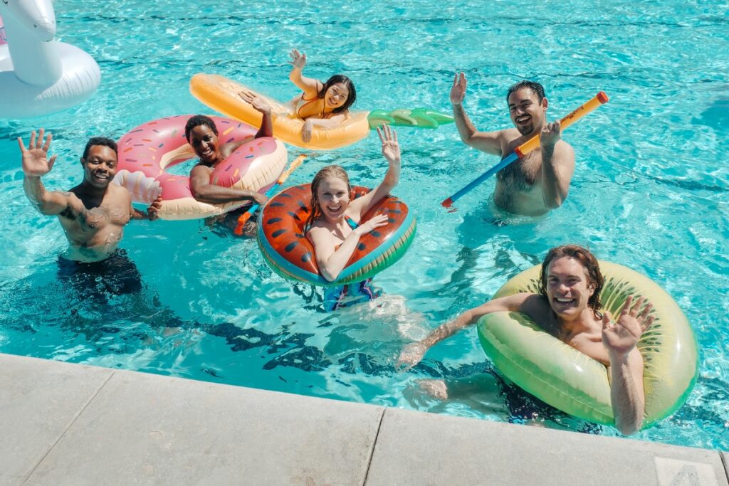 A group of people swimming with inflatable floats in a uniquely shaped pool.