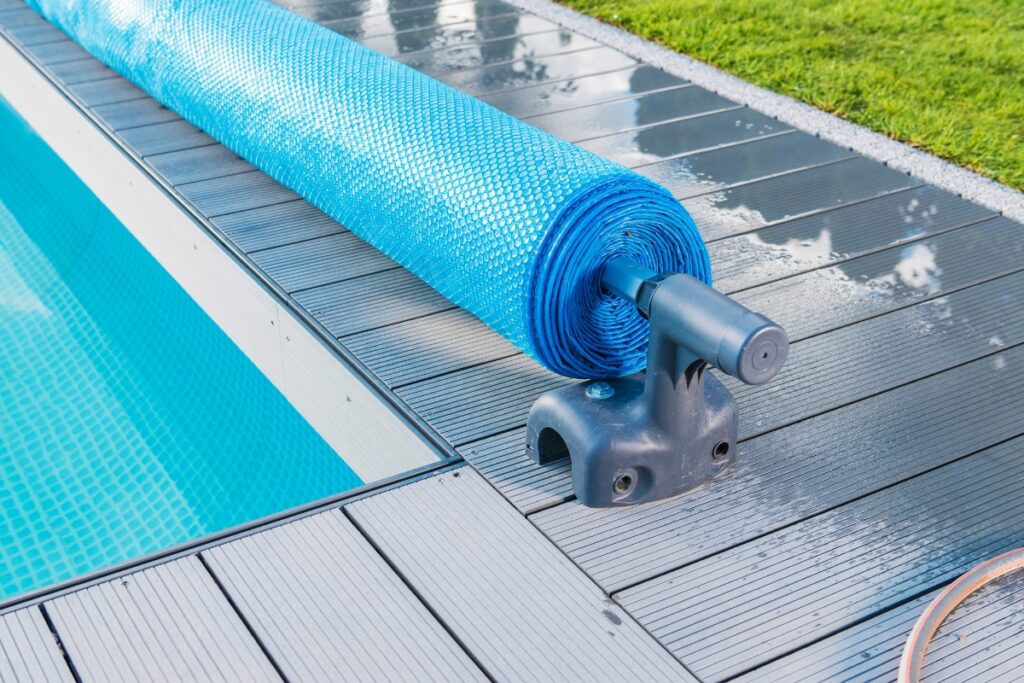 A blue tarp is attached to the side of a swimming pool for closing pool for winter.