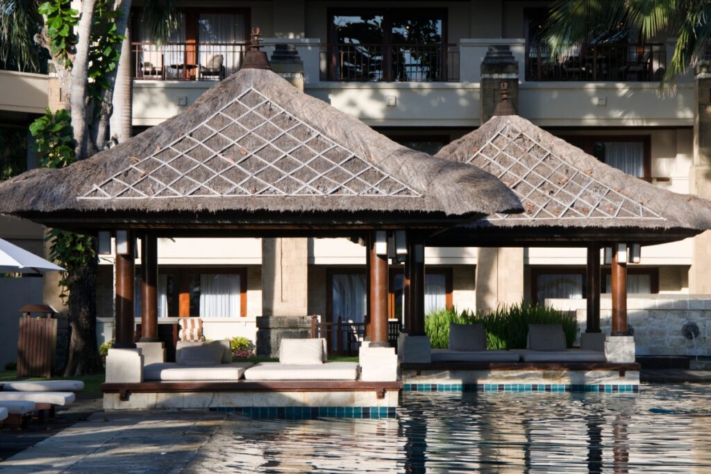 A pool cabana with a thatched roof.