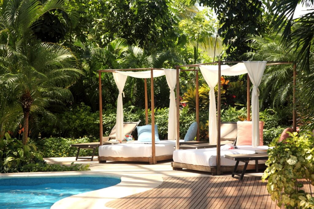 A pool with lounge chairs, umbrellas, and pool cabana.