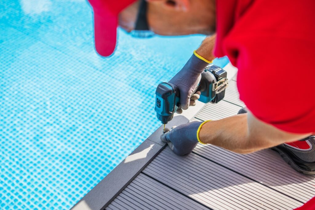 A man in a red shirt is working on a pool deck made of durable material.