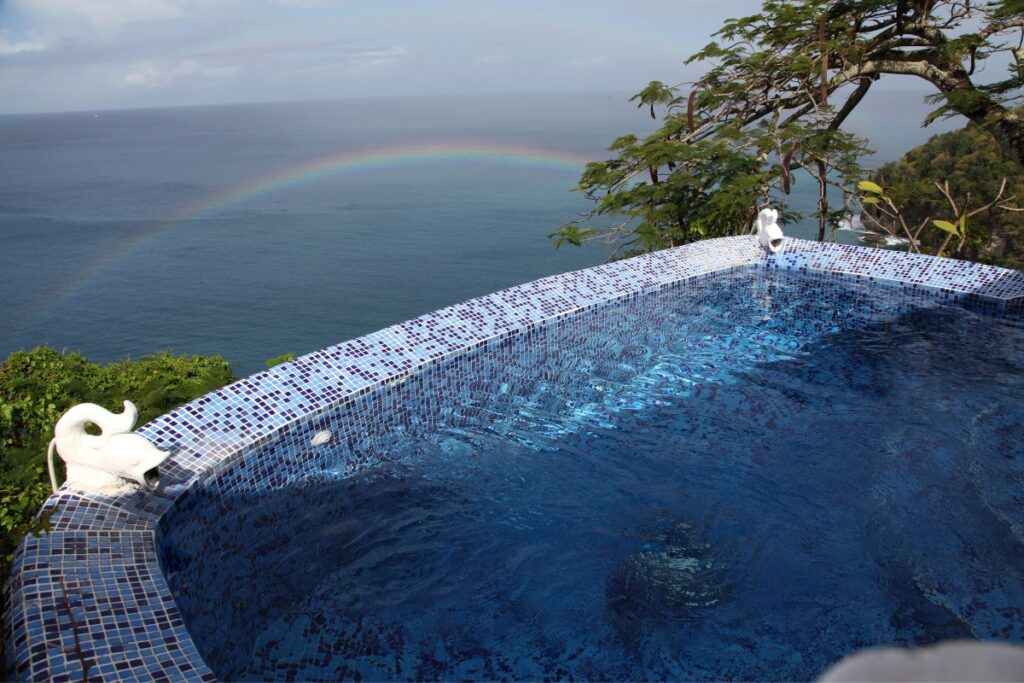 An inground pool with a rainbow in the sky.