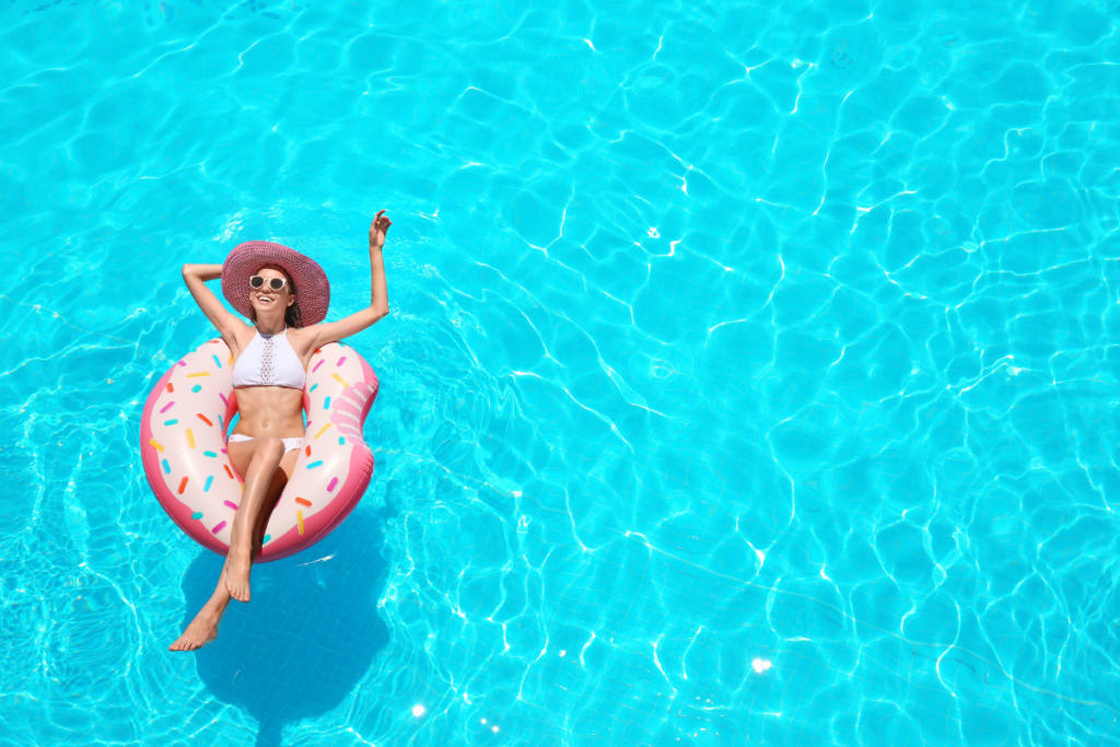 A woman relaxes on an inflatable raft in a swimming pool.