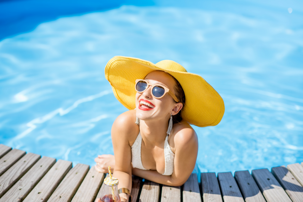 A woman in a swimsuit and hat enjoying a day by the pool.