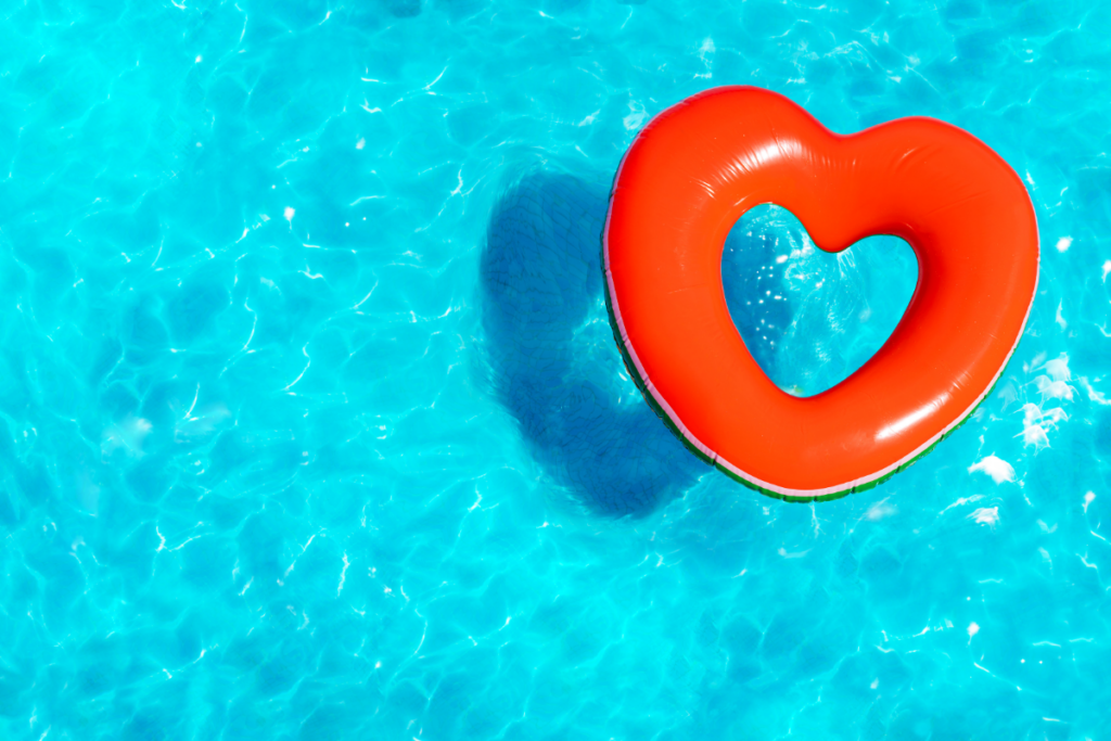 A heart-shaped inflatable float floating in a pool.