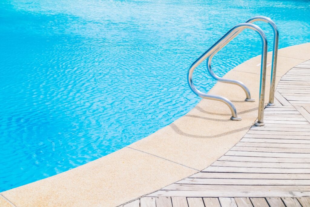 A swimming pool with a wooden deck, an energy-efficient ladder, and energy-efficient pools.