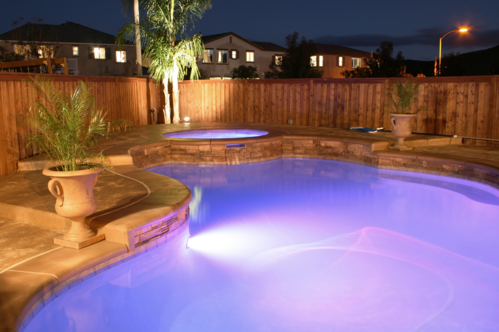 Illuminated outdoor pool with blue lights at twilight.
