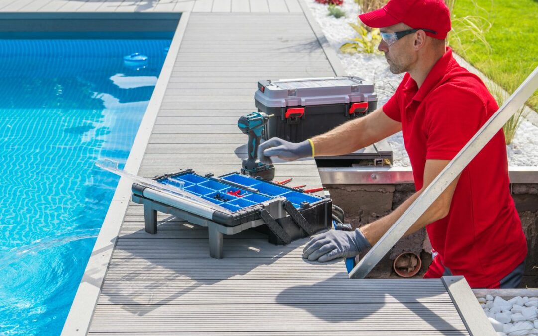 A person engaged in seasonal pool maintenance, working on a pool deck with a drill and a toolbox.