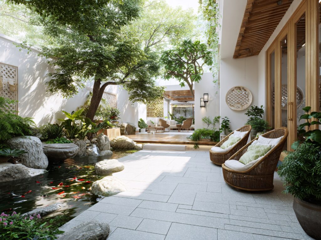A modern patio with wicker chairs overlooks a koi pond bordered by natural stone patios and lush greenery, with an open seating area in the background.